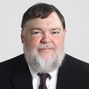 A headshot of Robert Scates, PhD, wearing a black suit with a red tie