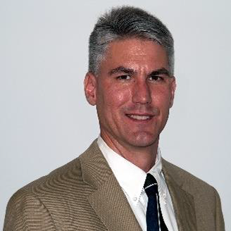 A headshot of Aaron Miller, MSc-PE wearing a tan blazer with a dark tie