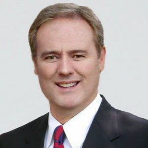 A headshot of Andrew Stringer, PE wearing a dark suit with a red tie and a white button-down shirt