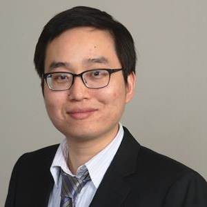 A headshot of Ye Xin, PhD, wearing a suit with a striped button up and a tie.